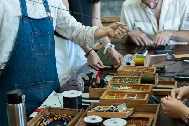 participants stringing colorful beads at a craft workshop table
