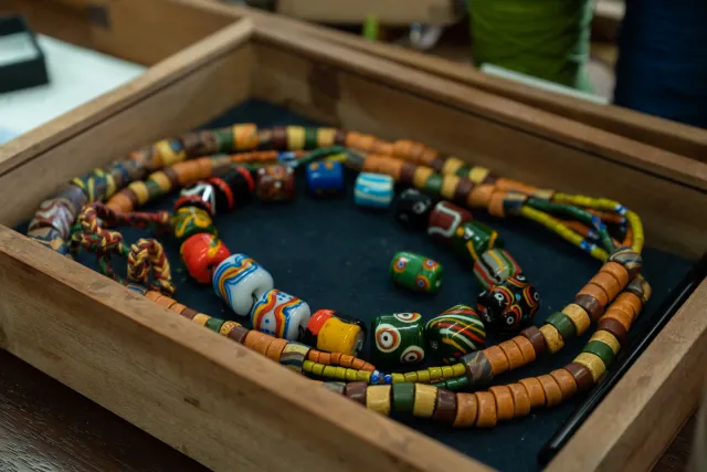 Colorful indigenous glass and wooden bead necklaces displayed in a wooden tray
