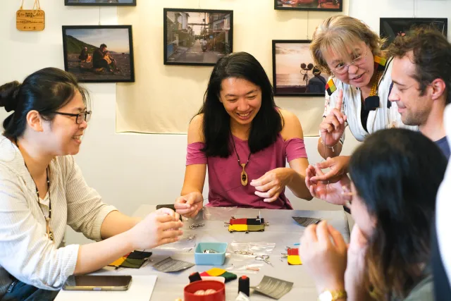 participants laugh and handle small craft materials together around a table