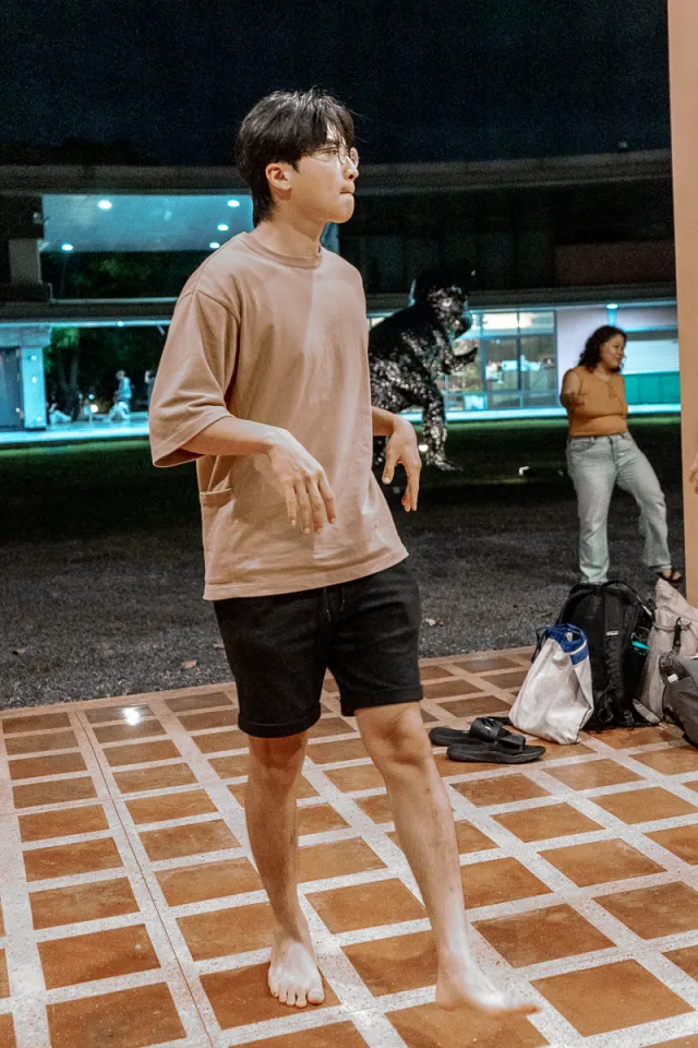 A young man dances barefoot on a tiled plaza at night