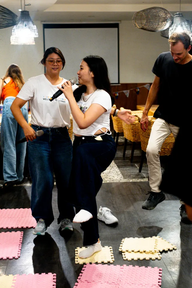 Two women playing a stepping-mat floor game indoors at a casual event