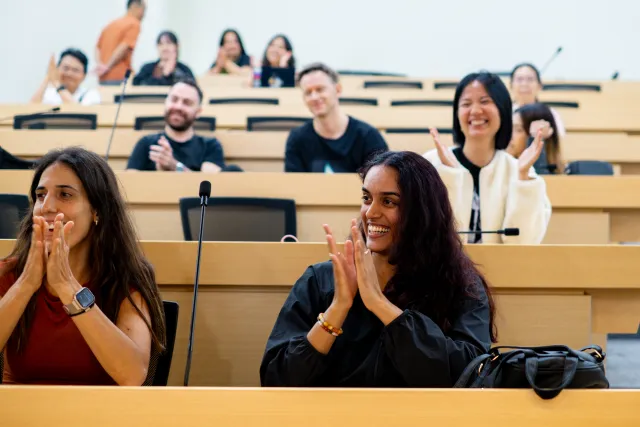 Audience members smiling and applauding during a lecture hall session