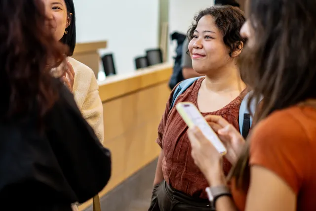 A smiling woman listens attentively during a small indoor group discussion