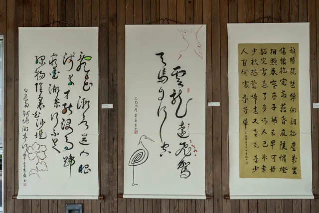 Three Chinese calligraphy scrolls displayed on a wooden wall