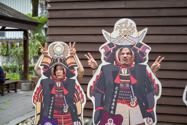 Two visitors pose playfully through samurai costume cutout boards at Qingxiu Temple