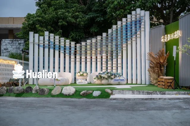 Outdoor event installation with tall white cylindrical pillars and "Hualien" signage at dusk
