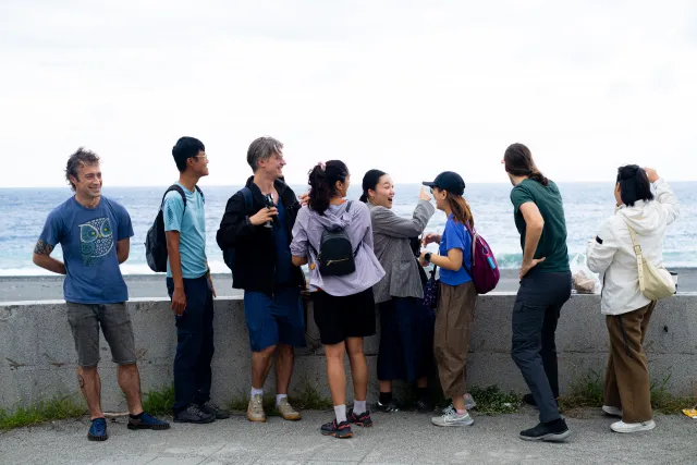 A group of people laughing and chatting together by a seaside wall