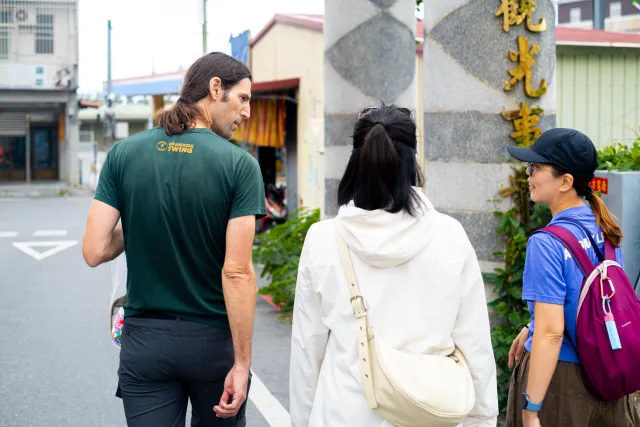 Three participants chatting on a quiet street outside a building entrance