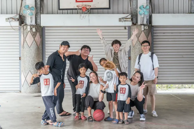 Group of adults and children posing cheerfully on an outdoor basketball court