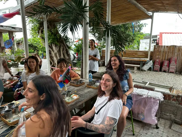 Participants laugh and chat together at an open-air craft workshop table