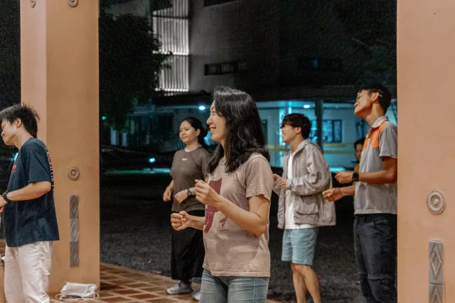 Young people smiling and dancing outdoors at night under warm lighting