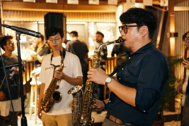 Two saxophonists perform at an intimate indoor jazz night before a crowd