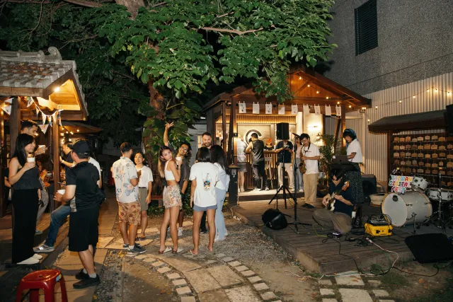 Guests mingle and dance in a warmly lit outdoor courtyard while a band performs at night