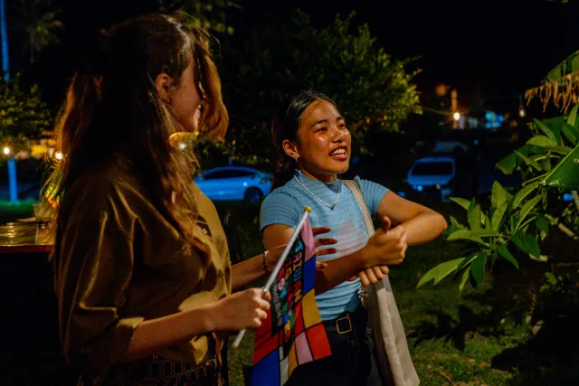 Two young women chat and laugh outdoors at a night event