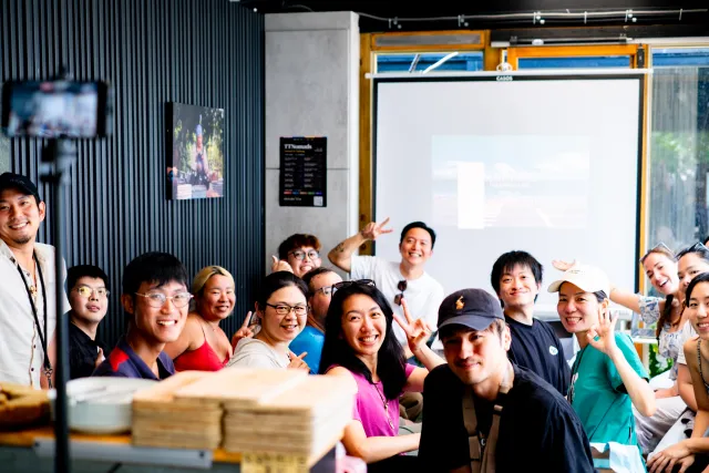 A group of smiling participants pose together indoors during a community meetup event