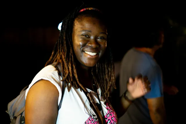 A smiling woman with dreadlocks looks at the camera at an outdoor night event