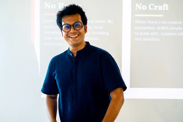 A smiling speaker stands in front of a presentation slide reading "No Craft" in a bright indoor venue