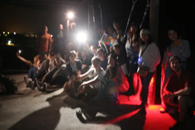 A large group of young people gathered outdoors at night under artificial lights