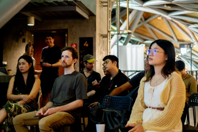 Audience of mixed attendees seated and listening attentively at an indoor talk session