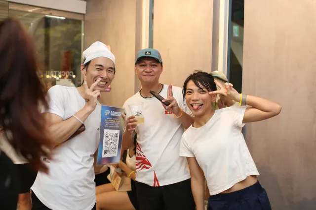 Three cheerful participants in white tees pose playfully indoors after a run event