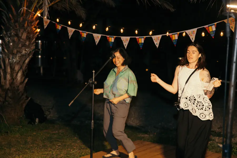 Two people dancing under string lights at the night market