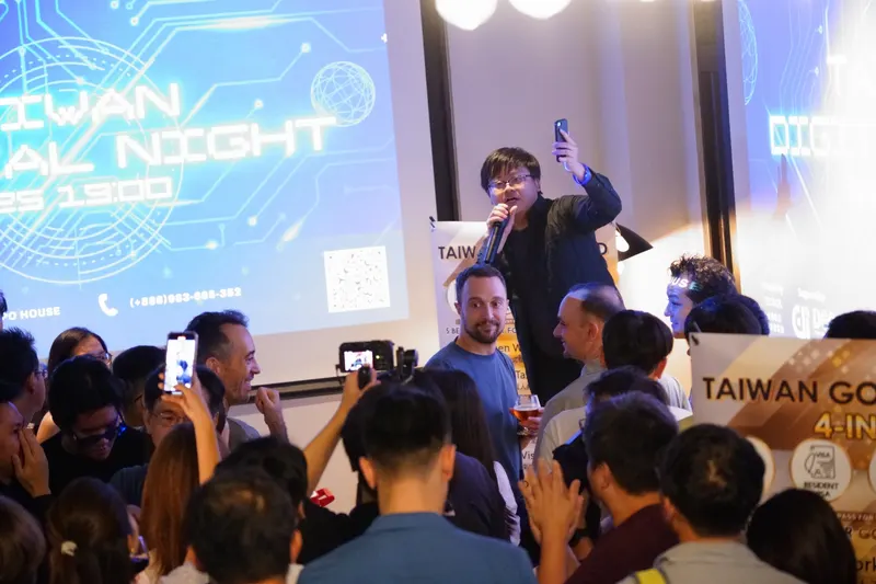 A speaker addresses a packed room beneath the Taiwan Digital Night screen