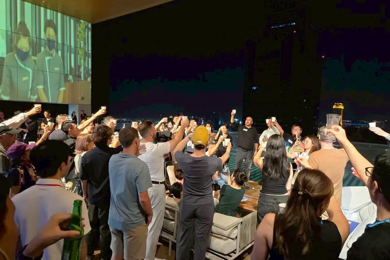 A rooftop crowd raises their glasses beside the pool and Kaohsiung skyline